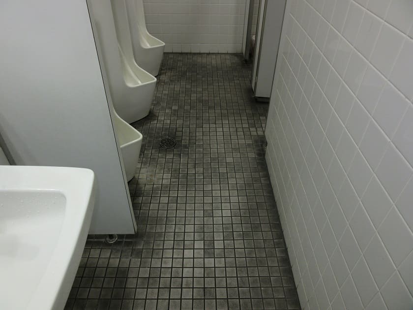 清掃前の男性用トイレの床面|タイル部分に経年による汚れが目立つ状態を記録したビフォー画像