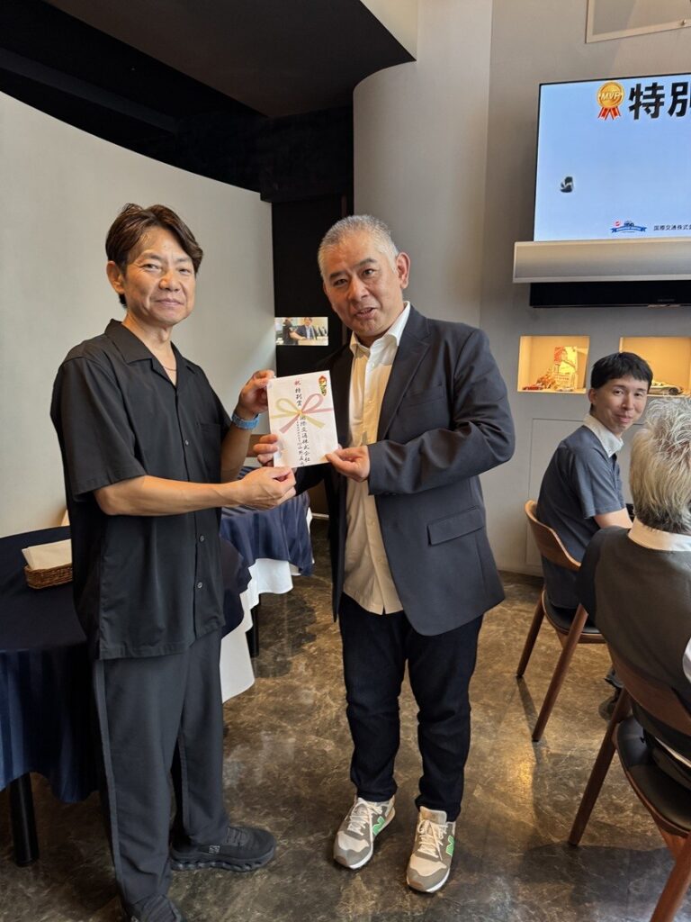 国際交通株式会社の社内表彰式で、特別賞を受賞した社員が代表者から賞状を授与されている様子を写した写真