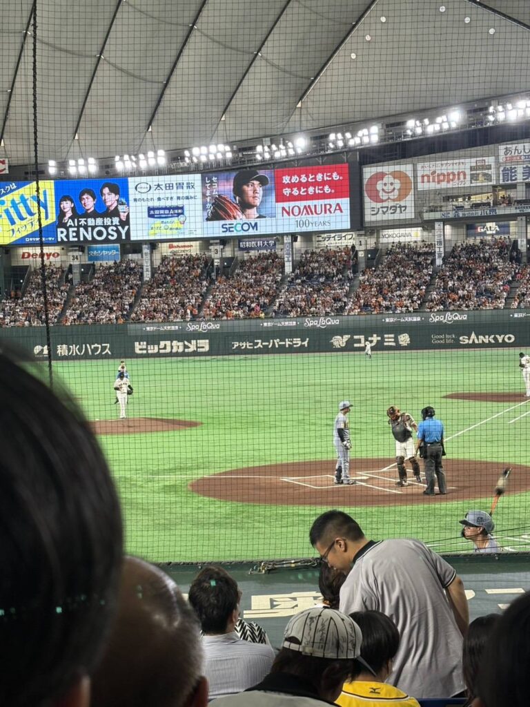 国際交通社員の東京ドームで行われた読売ジャイアンツ戦の試合風景。グラウンドでは試合が進み、多くの観客で球場が賑わっている。